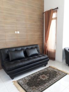 巴图Villa Puncak Garuda A5的客厅里设有一张黑色皮沙发,配有窗户