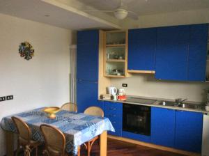 阿巴迪亚拉里亚纳La Meridiana sul Lago的厨房配有蓝色橱柜和桌椅