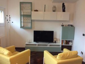 阿巴迪亚拉里亚纳La Meridiana sul Lago的客厅配有2把黄色椅子和平面电视