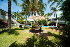 埃尔利海滩芒果屋度假酒店的游泳池旁带遮阳伞的野餐桌