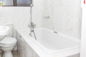 哈博罗内黄金街道旅馆的浴室配有白色浴缸和卫生间。