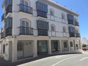 内尔哈Hostal Boutique Doña Carmen - Adults Recommended的白色的建筑,设有黑色阳台,位于街道上