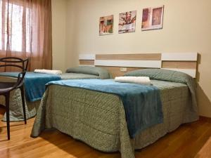 阿尔苏阿De Camino vivienda de uso turístico的客房内的三张床,上面有蓝色的毯子
