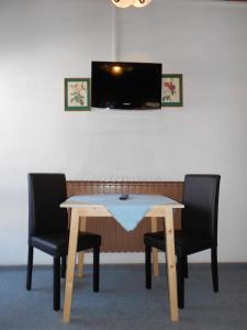 恩斯塔尔豪斯涛若号夫膳食公寓酒店的一张桌子、两把椅子和一台电视机