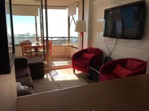 康康Gran departamento con vista al mar的客厅配有红色椅子和平面电视