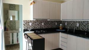 巴拉奈里奥-坎布里乌Residencial Recanto Paraíso BC - Flat的厨房配有白色橱柜和黑色台面