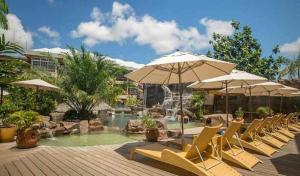 帕拉马里博杰卡纳亚马逊疗养度假酒店的一组椅子和遮阳伞,位于游泳池旁