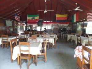 尼格瑞尔Jah B's Cottages on Beach Road-Negril的餐厅设有桌椅和天花板上的旗帜
