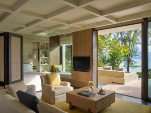 芭东海滩Rosewood Phuket的一间带一张床的房间和一间带电视的客厅