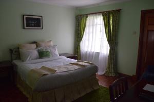 内罗毕阿迪斯花园套房旅馆的一间卧室设有一张大床和一个窗户。