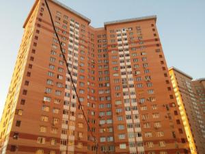 波多利斯克InnDays Ленинградская 11的一座高大的橙色公寓楼,设有窗户