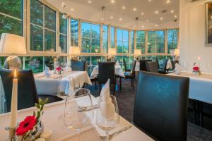 莱比锡温多夫西佳酒店的餐厅设有桌椅和窗户。