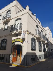 卡沃内拉斯Hostal San Andres的白色的建筑,设有橙色的门和阳台