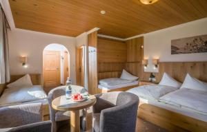 卡顿巴赫加尼克劳科尔酒店的一间卧室配有两张床和一张桌子及椅子