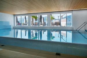 韦吉斯Alpenblick Weggis - Panorama & Alpen Chic Hotel的水中反射的建筑物中的游泳池