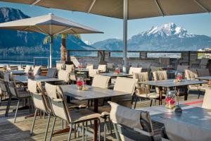 韦吉斯Alpenblick Weggis - Panorama & Alpen Chic Hotel的餐厅配有桌椅,位于山脉的背景中