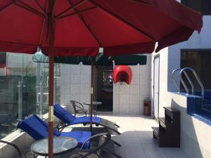 贝鲁特Midtown Hotel & Suites的一个带桌椅和红色遮阳伞的庭院