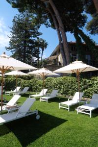 迪亚诺马里纳La Casa di Anny camere di Charme Citr 8027的一群白色的椅子和遮阳伞在草地上