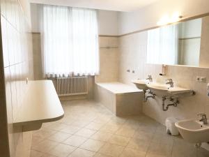梅拉诺曼佐尼客房酒店的浴室配有两个盥洗盆、浴缸和盥洗盆。