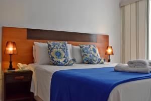 亚松森Giuseppe Suites Hotel的一间卧室配有一张带蓝色毯子的大床