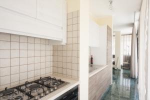 拉卡莱Attico Saker的厨房设有白色瓷砖墙壁和炉灶烤箱。
