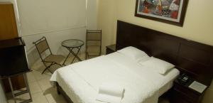 皮乌拉Rivera del Rio Hotel的卧室配有一张床和一张桌子及椅子