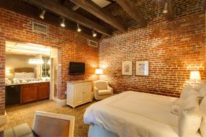 新奥尔良多菲内新奥尔良酒店的砖墙卧室配有一张床和镜子