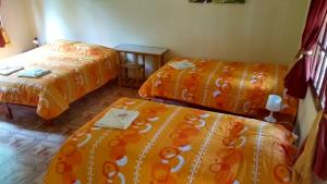 奥克萨潘帕La Casa Oxapampina的配有橙色床单的客房内的两张床