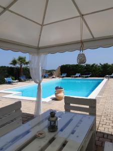 卡斯特拉纳格罗泰Il Piccolo Rifugio的一个带桌子和白色遮阳伞的游泳池