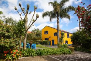 卡佩拉什Quinta das Flores的棕榈树和植物的黄色房子