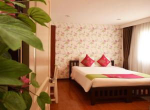 曼谷拉查达毕莉斯酒店的一间卧室配有带粉色和绿色枕头的床