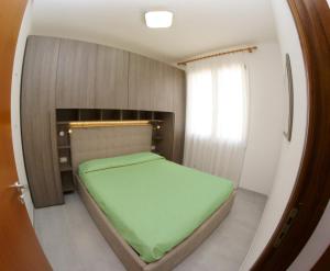 马达莱纳蓝光白塔酒店的一间小卧室,房间内设有一张绿色的床