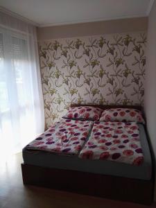 豪伊杜索博斯洛Kiskuckó Apartman的一间卧室配有一张带花卉壁纸的床