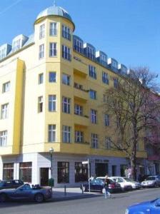 柏林柏林猎户座酒店的一座黄色的建筑,前面有汽车停放