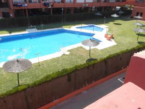 阿尔赫西拉斯Apartamento a la Playa的享有带遮阳伞的游泳池的顶部景致