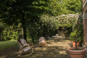 马切拉塔Dimora Rosa Bianca的花园设有椅子和鲜花桌子