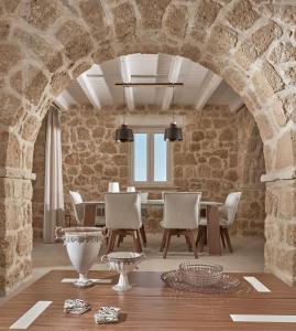 瓦西里科斯Arismari Luxury Villas的一间设有石墙和桌椅的用餐室