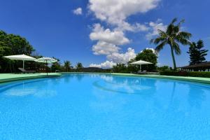 宇流麻冲绳可可花园酒店的一个带两把白色遮阳伞的大型蓝色游泳池