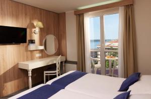 波尔托罗Hotel Mirna - Terme & Wellness Lifeclass的配有一张床、一张书桌和一扇窗户的酒店客房
