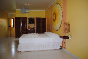 帕里普埃拉Fazenda Fiore Resort的卧室配有白色的床和黄色的墙壁