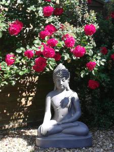 SeigyStudio & Gîte Zen de Beauval- 800 m du Zooparc的坐在粉红色玫瑰前的女人雕像