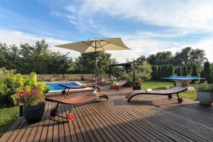 瓦图拉Villa NaNa - modern Villa with a pool surrounded by nature, Istria-Pula的一个带长椅和遮阳伞的甲板和游泳池