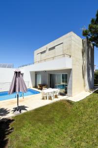 维拉·雷阿尔·德·桑托亚Pé na Areia - Guest House的一座带游泳池和遮阳伞的现代房子