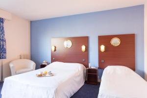 勒阿弗尔勒阿弗尔波彭斯莱斯让德马尔酒店的一间酒店客房,配有两张床和一张床上的食品托盘