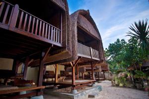 蓝梦岛郎邦巴厘岛小屋酒店的一座大型木制建筑,设有阳台和桌子