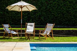 卡米尼亚Liiiving in Caminha | Countryside Pool House的游泳池旁的两把椅子和一把遮阳伞