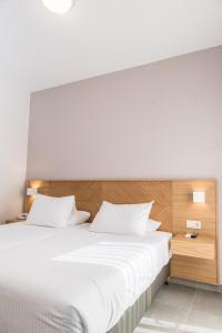 干尼亚克雷塔埃琳娜酒店的卧室配有白色的床和木制床头板