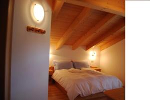 卡纳泽伊Appartamenti Chalet Orchidea的卧室配有白色床和木制天花板