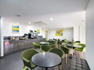 悉尼绿色广场价值酒店的餐厅设有桌子、绿色椅子和柜台