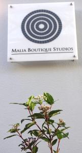 玛利亚Malia Boutique Studios的墙上的标志,前面有植物